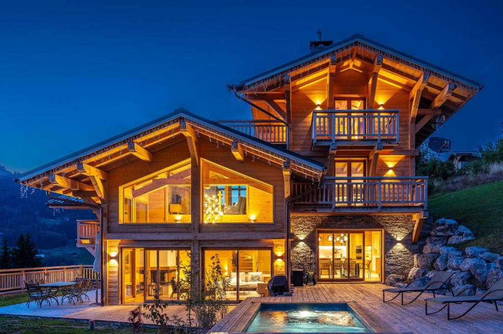 une grande maison en rondins avec une piscine en face de celle-ci dans l'établissement Chalet Valerie, aux Gets