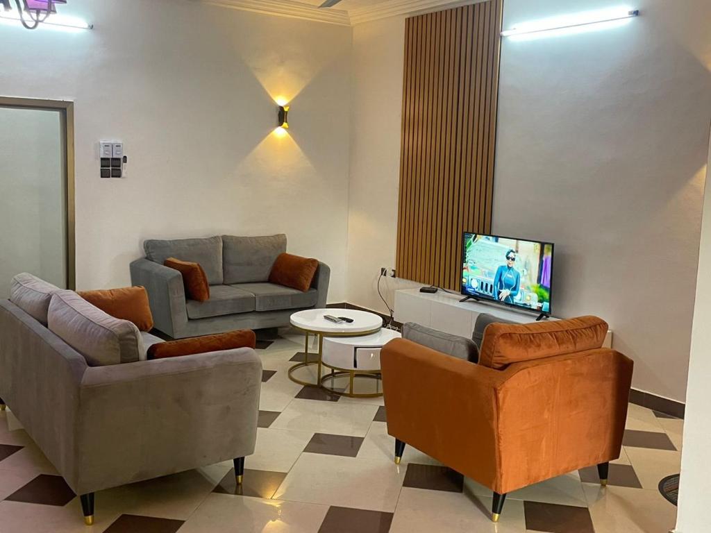 sala de estar con sillas, TV y sofá en Les Appartements Junior, en Cotonou