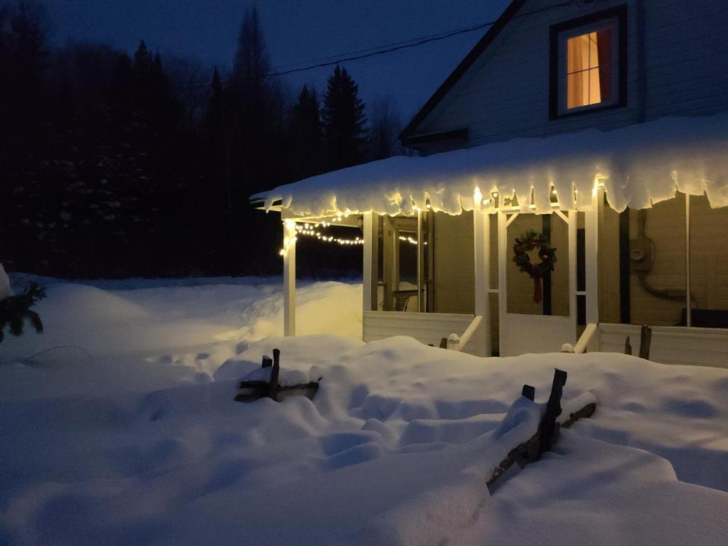 une maison recouverte de neige la nuit avec des lumières dans l'établissement La Sacacomie Unique, Petit déjeuner bio, Grand terrain, table de Pool, à Saint-Alexis-des-Monts