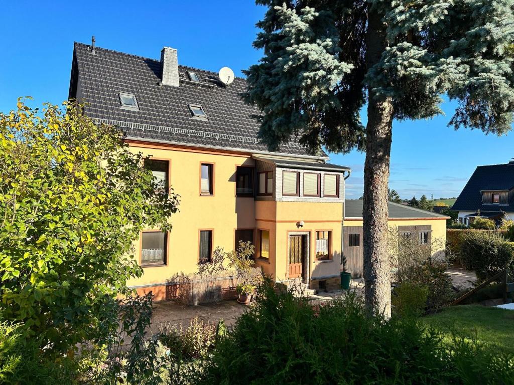 uma casa amarela com um telhado preto e uma árvore em Beautiful holiday apartment in Stolpe em Stolpen
