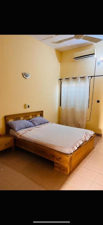 ein Schlafzimmer mit einem Holzbett und einem Fenster in der Unterkunft Maison meublée à Calavi à 2mn du supermarché EREVAN in Abomey-Calavi