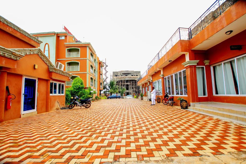 eine Kopfsteinpflasterstraße in einer Stadt mit orangefarbenen Gebäuden in der Unterkunft Benin Metropole Hotel in Parakou