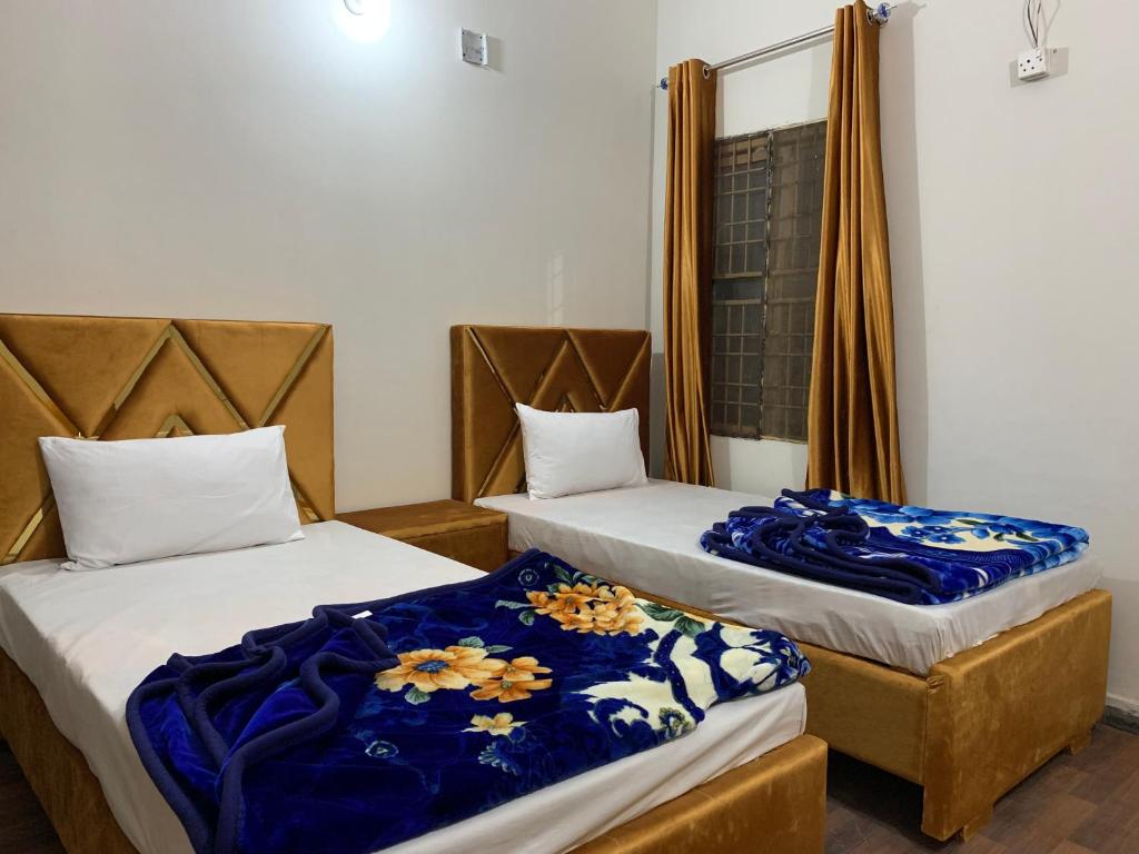 two beds in a room with blue blankets on them at Eden Plus Executive Hotel in Lahore