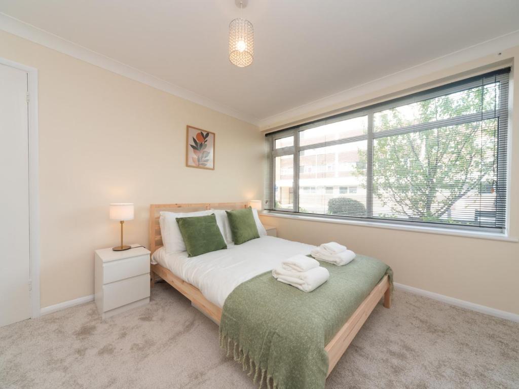 a bedroom with a bed and a large window at Pass the Keys Great apt 20 mins central London in Surbiton