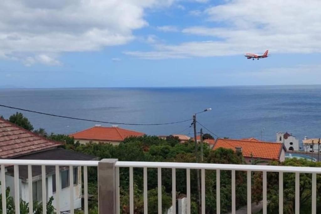 a plane flying over a house with the ocean at Sol e Mar by the airport in Santa Cruz