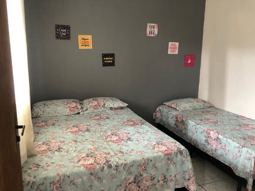 2 camas en un dormitorio con carteles en la pared en Kitnet do Costa Praia do Pereque Guaruja!!!, en Guarujá