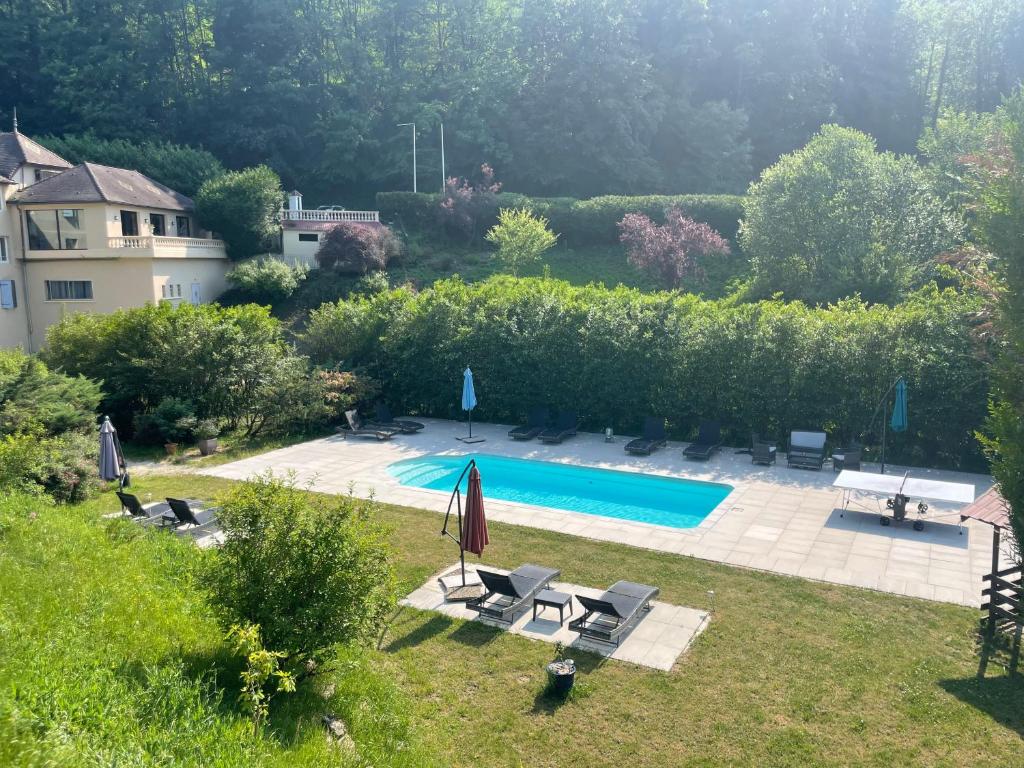 a pool in a yard with chairs and umbrellas at Domaine Du Moulin Vallée Heureuse in Poligny