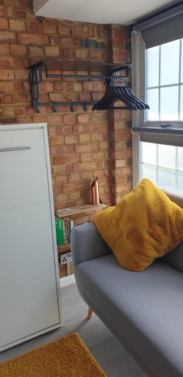 a living room with a couch and a brick wall at Tiny home whole flat beach cabin in Southwick