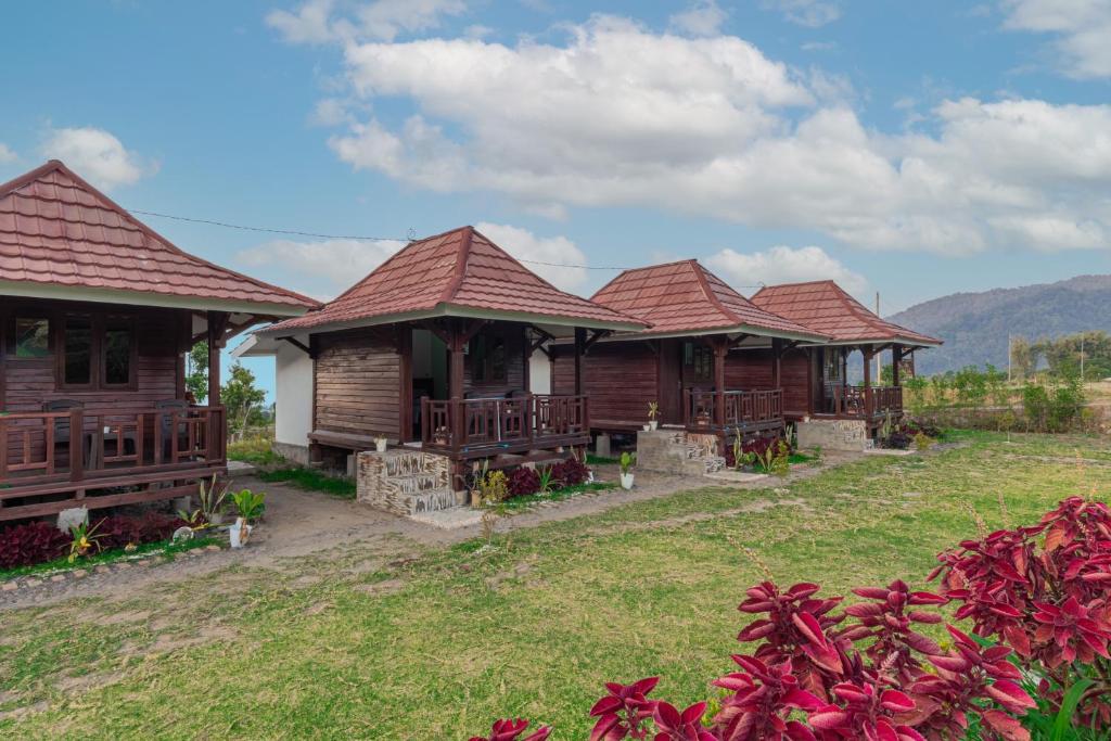 a row of wooden houses with mountains in the background at Bale Gantar in Sembalun Lawang