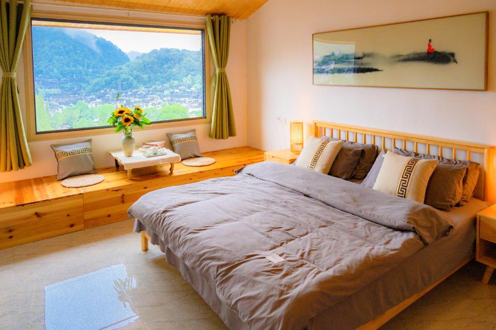 um quarto com uma cama grande e uma janela grande em 云起山居庭院观景民宿 em Fenghuang