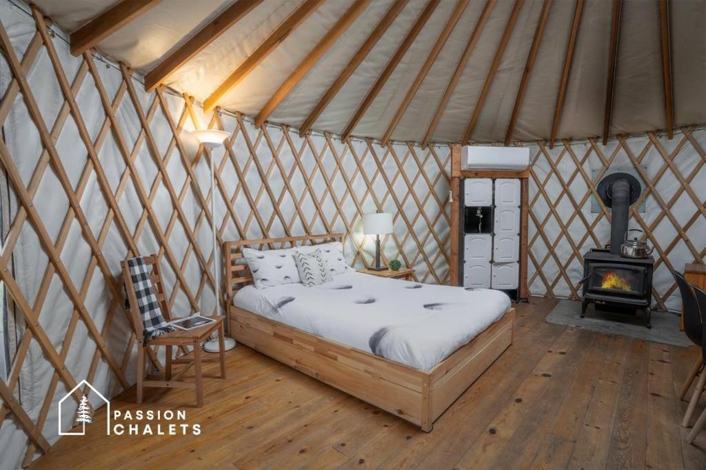 a bedroom with a bed in a yurt with a stove at La Lumineuse des yourtes du petit ruisseau in Mandeville