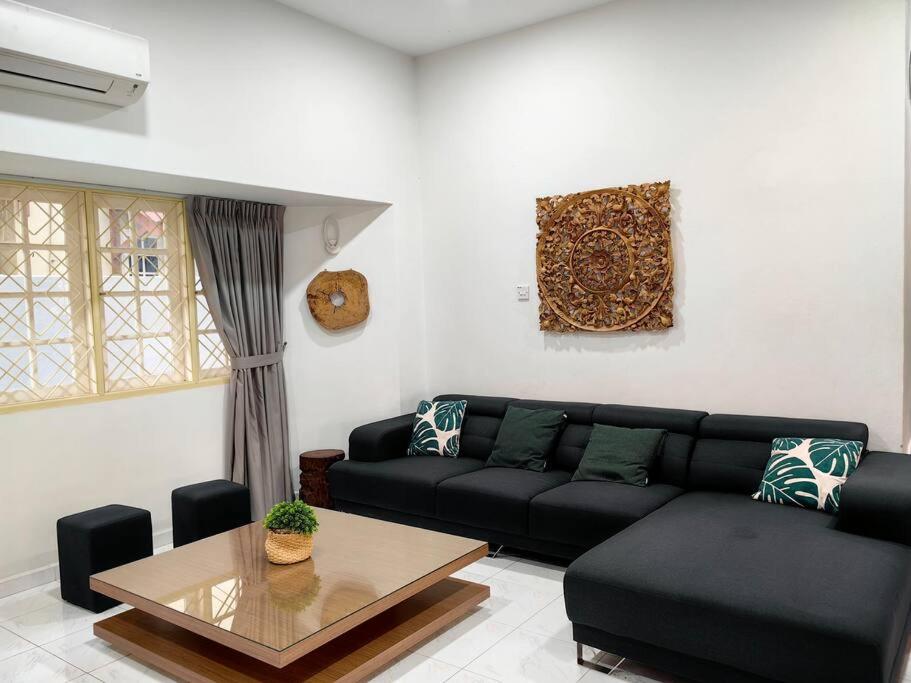een woonkamer met een zwarte bank en een tafel bij Klebang Spacious Comfy Bangalow in Kelebang Besar