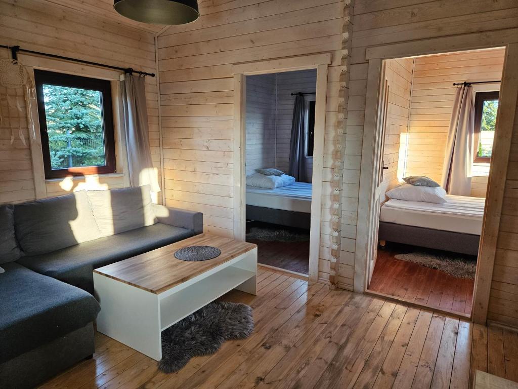 una sala de estar con sofá y una habitación con 2 camas en Domek całoroczny MAGJAN z sauną en Złotów
