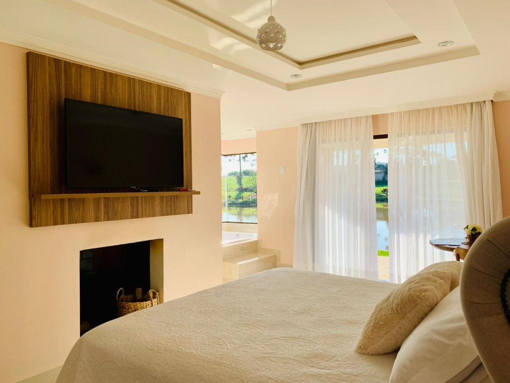 a bedroom with a bed with a fireplace and a flat screen tv at Hope Valley Adventure Resort in Guarapuava