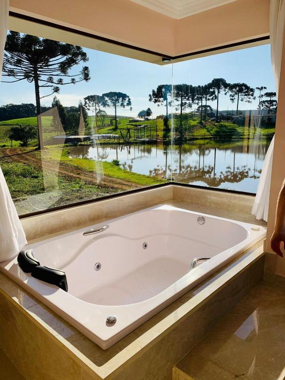 a bath tub in a room with a large window at Hope Valley Adventure Resort in Guarapuava