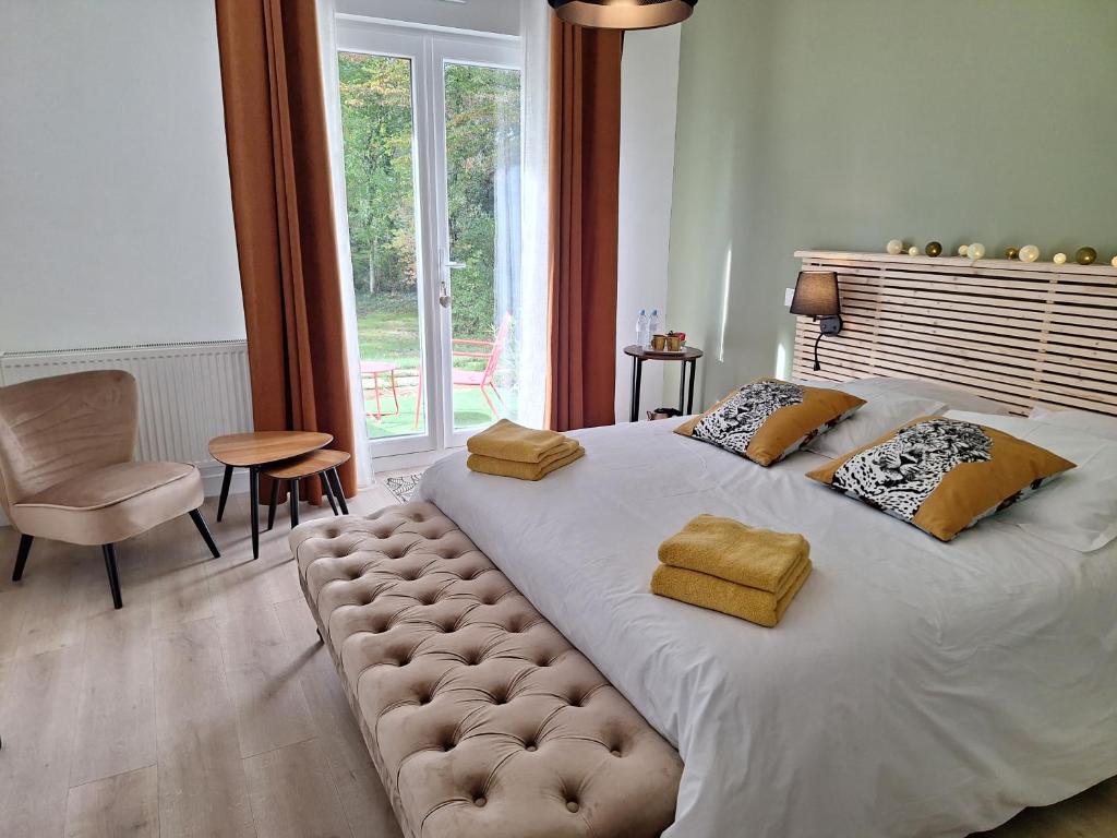 a bedroom with a large white bed with a large window at Le pré du buis in Yvré-lʼÉvêque