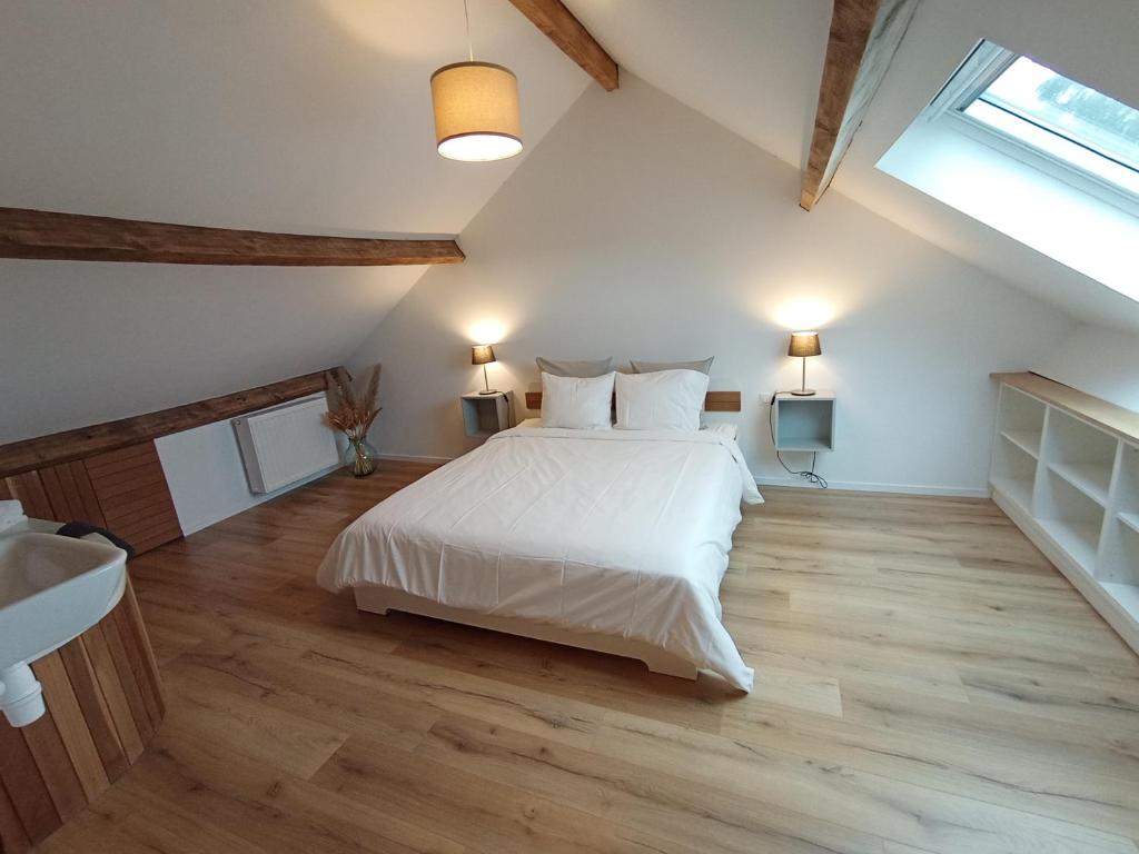 um quarto com uma grande cama branca num sótão em L'Escale Buissonnière - Cosy and quiet house em Rochefort