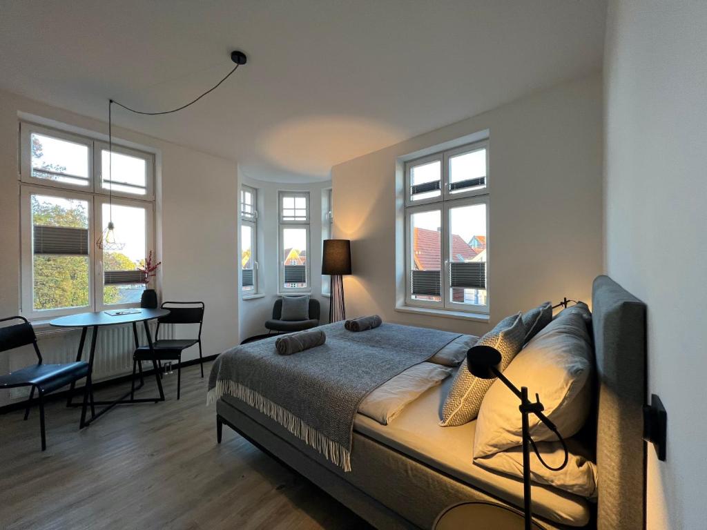 a bedroom with a bed and a table and windows at Apartmenthaus Buxtehude St -Petri-Platz Apt 4 in Buxtehude