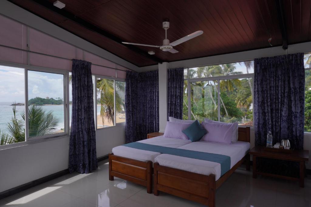 a bedroom with a bed with a view of the water at SURF UNA BEACH HOTEL in Unawatuna
