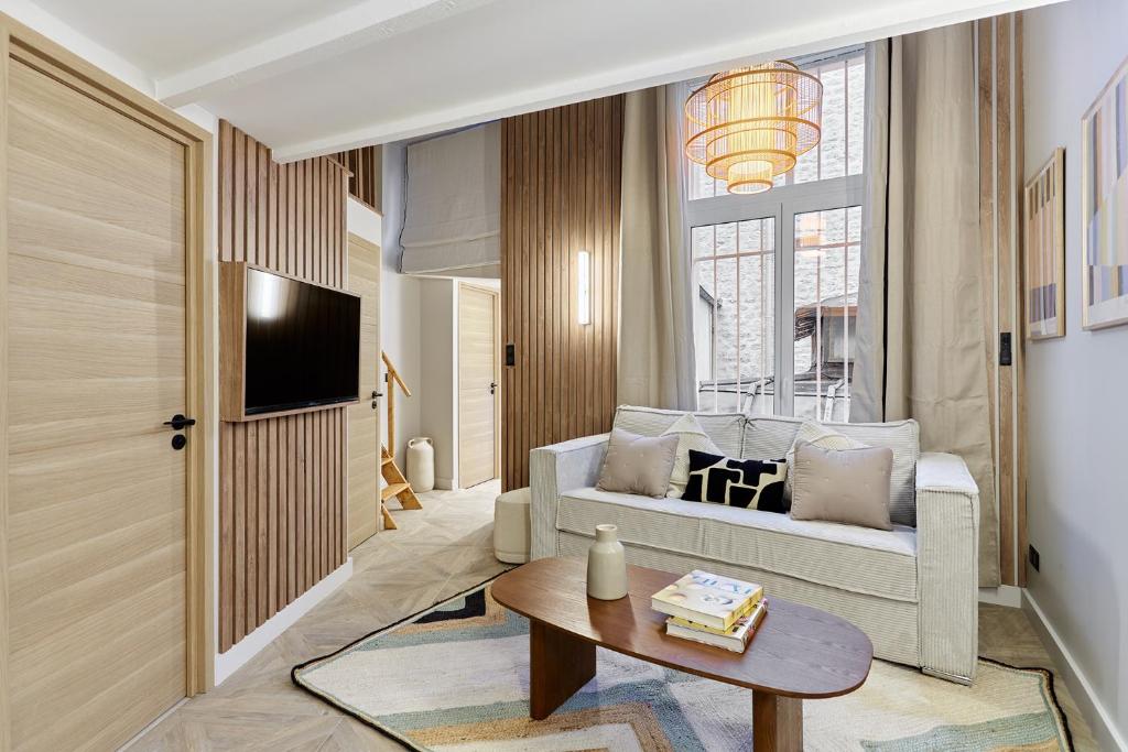 een woonkamer met een bank en een tafel bij Apartment Batignolle Montmartre by Studio prestige in Parijs