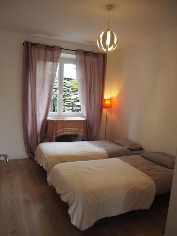 three beds in a room with a window at Le Cocon in Millau