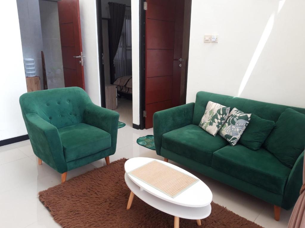 a living room with a green couch and two chairs at Koral Guesthouse in Malang