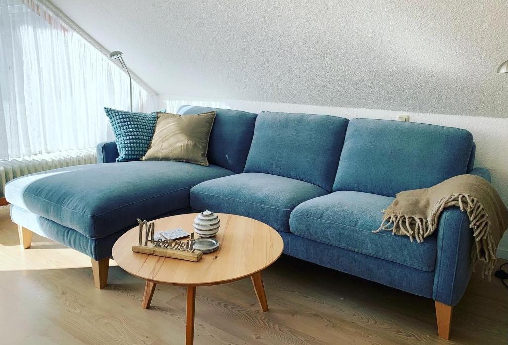een blauwe bank in een woonkamer met een tafel bij Gästehaus Windrose Wohnung 6 in Pelzerhaken