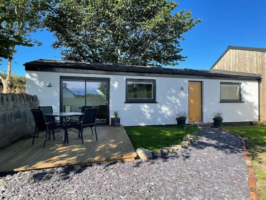 a small white cottage with a table and chairs at Tranquil, secluded, rural cottage for two in Beaumaris