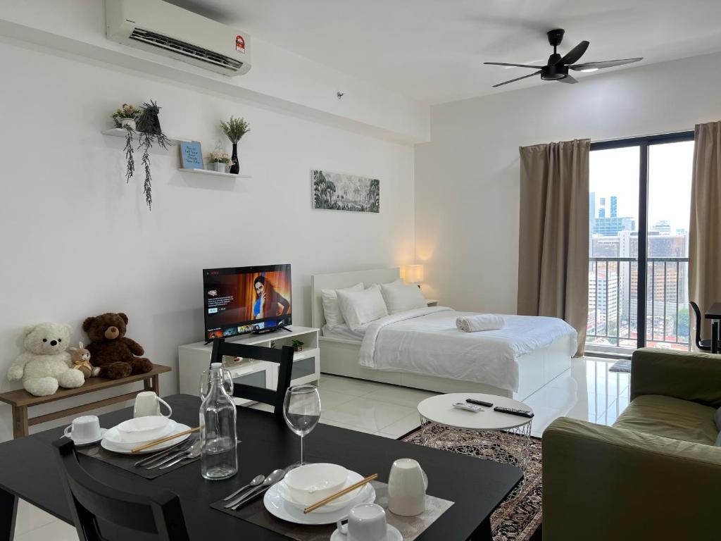 a white room with a bed and a table and a tv at Cozy luxury couple studio apartment chambers kl klcc kl tower view in Kuala Lumpur