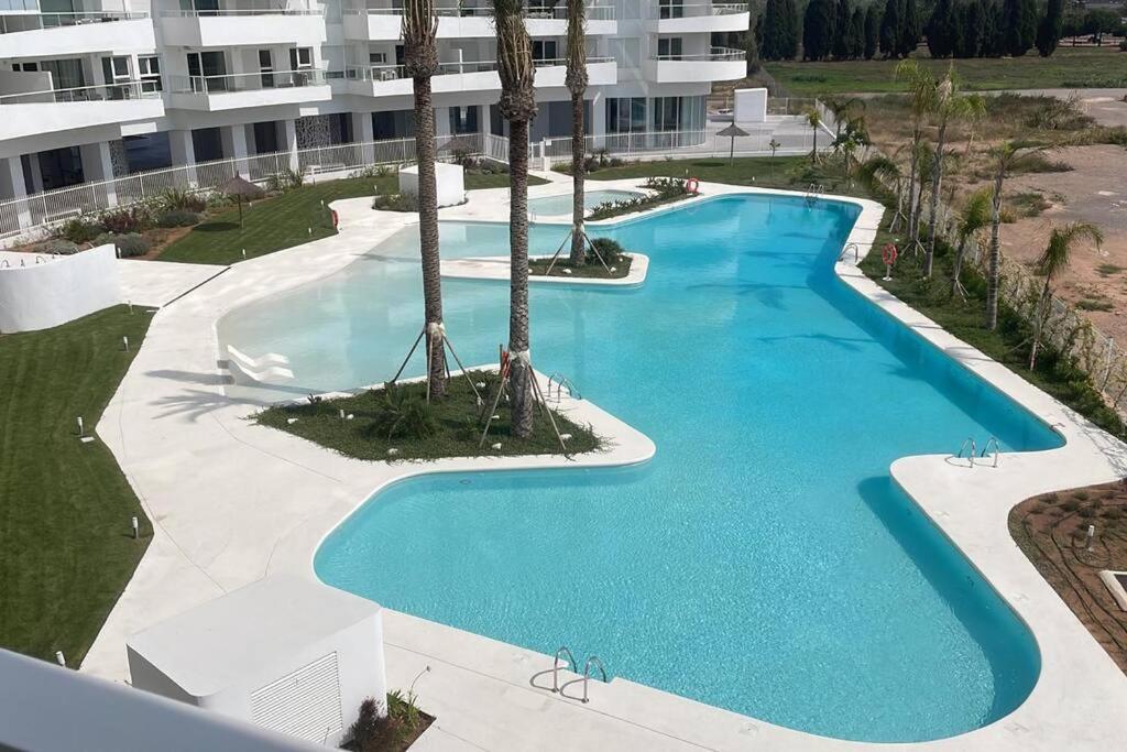 uitzicht op een groot zwembad met palmbomen bij Apartment in Emblematic Building in Canet de Berenguer