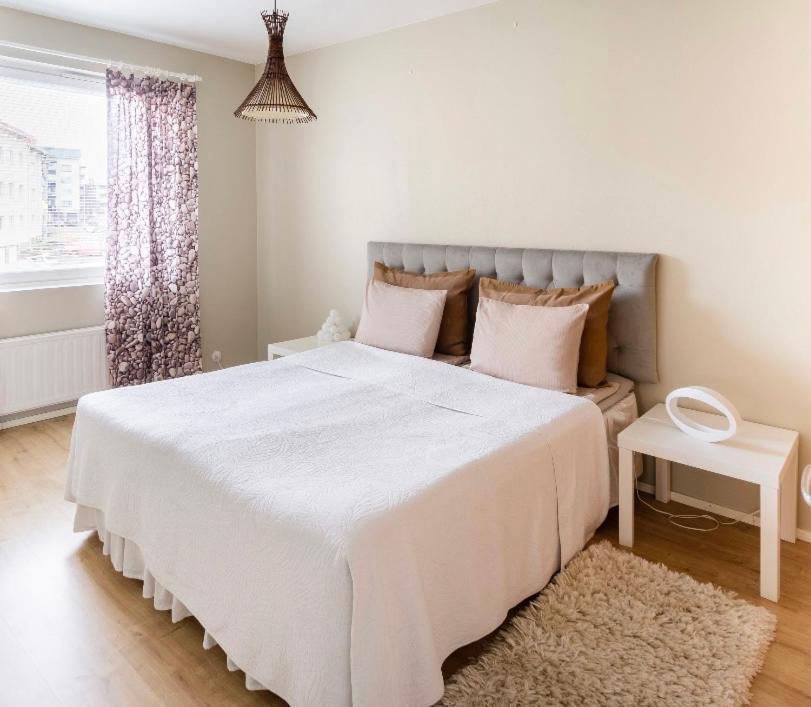 1 dormitorio con 1 cama blanca grande con almohadas rosas en FlatsinRoi Apartments en Rovaniemi