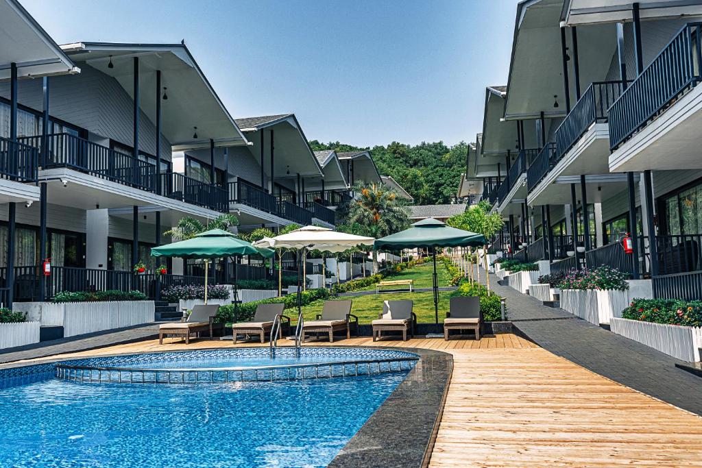 einen Pool mit Stühlen und Sonnenschirmen neben einem Gebäude in der Unterkunft Oralia Resort in Velha Goa