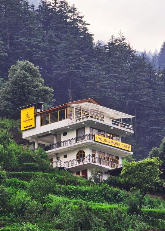 a building on the side of a hill with trees at Young Monk Homestay Jibhi in Jibhi