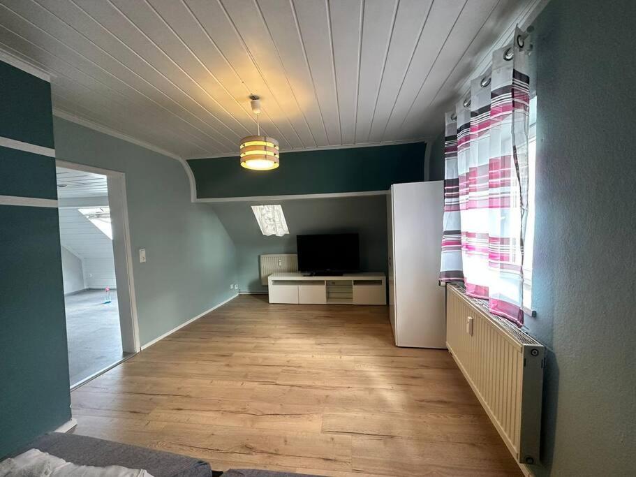 an empty living room with a refrigerator and a television at Gemütliche Wohnung in Pforzheim in Pforzheim