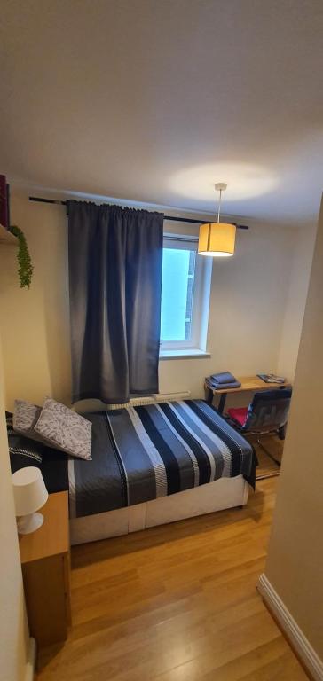 1 dormitorio con 1 cama y una ventana con cortina azul en Private Room&Bath near the Square Mile en Londres
