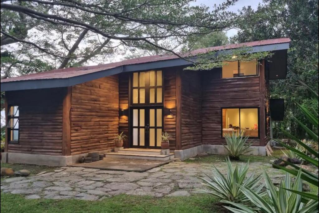 Country Villa Cagayán de Oro Filipinas في كاغايان دي أورو: كابينة خشبية مع شرفة أمامية ونوافذ كبيرة