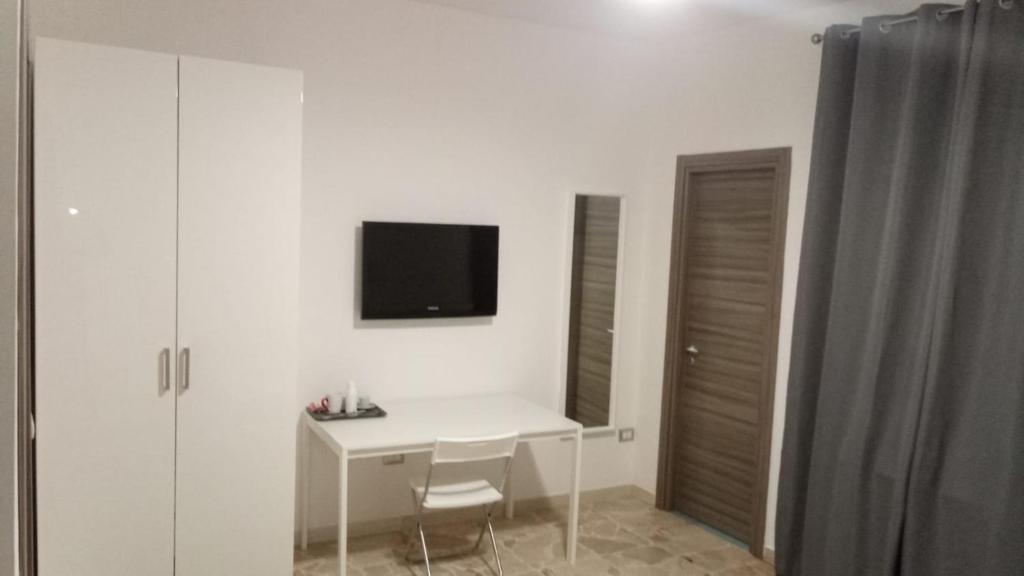 um quarto branco com uma secretária e uma televisão na parede em La Maison em Montallegro