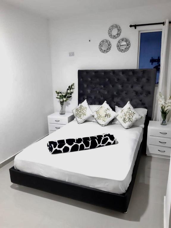 a bedroom with a bed with a black headboard and pillows at Hostal De la 8 in Barranquilla