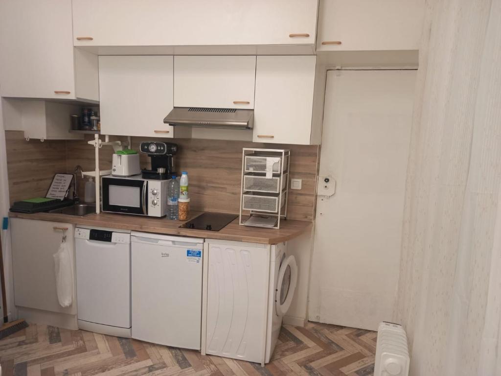 eine Küche mit weißen Schränken, einer Waschmaschine und einem Trockner in der Unterkunft Très joli petit studio aux portes Paris in Ivry-sur-Seine