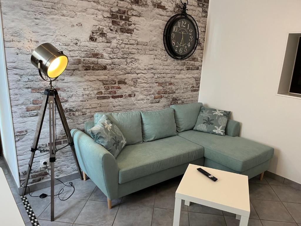 - un salon avec un canapé vert et un réveil dans l'établissement Le Parmentier, à Châlons-en-Champagne