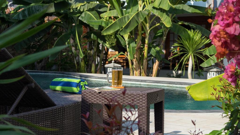 a table with a book on it next to a pool at Sanur Lodge in Sanur