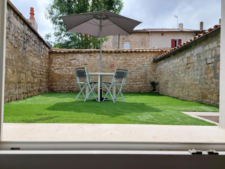 a table with two chairs and an umbrella in a yard at les locs d'Anaïs et David in Melle