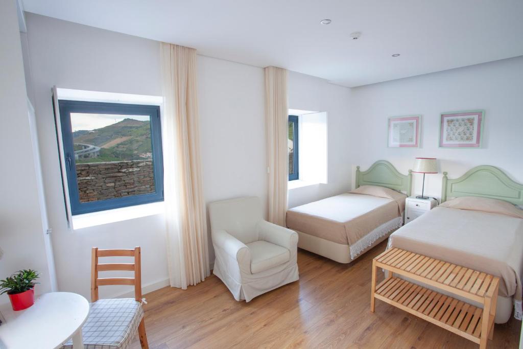 a bedroom with two beds and a chair and a table at Quinta da Pitarrela in Peso da Régua