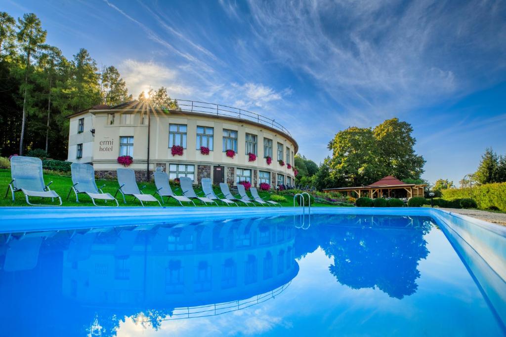 a house with a pool in front of a building at Hotel Ermi in Jince