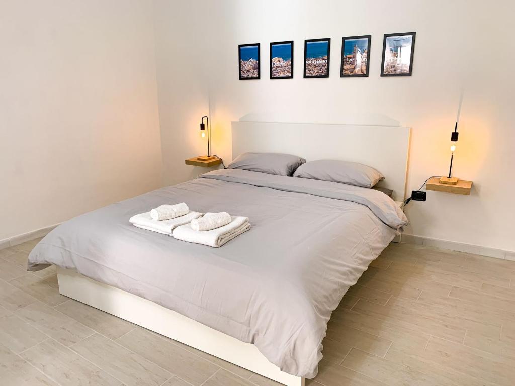 1 dormitorio con 1 cama blanca y 2 toallas en Le Vie del Borgo, en Sannicandro di Bari