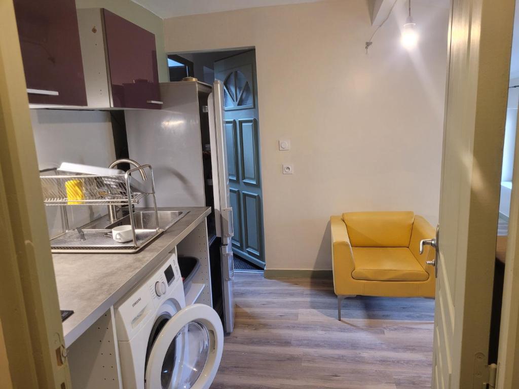 a kitchen with a sink and a yellow chair at studio 27m2 in Quissac