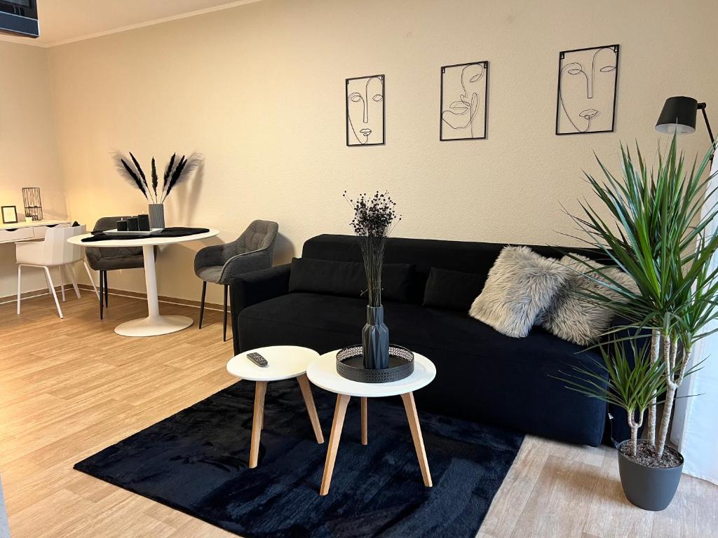 a living room with a black couch and two tables at Charming Homes - Studio 16 in Wolfsburg