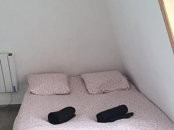 Una cama con dos almohadas negras encima. en Equipée 1 pièce proche Paris, en Argenteuil