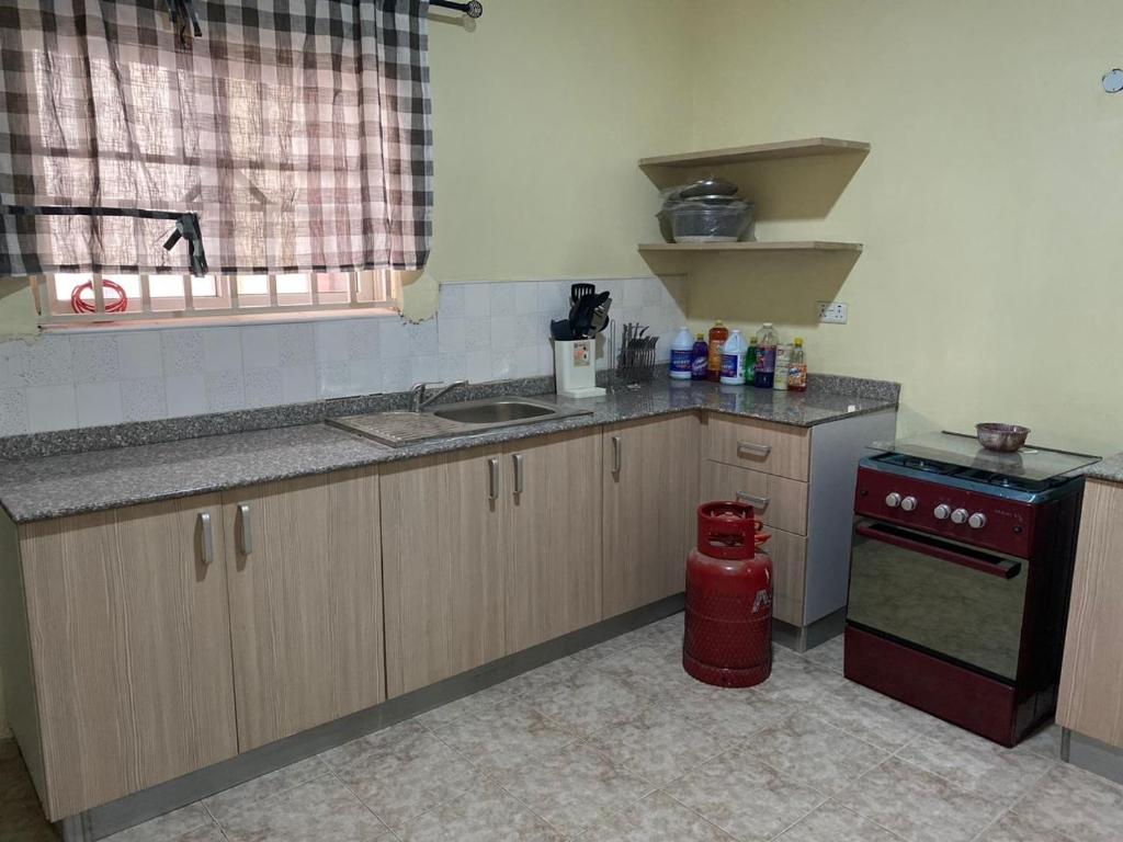 uma cozinha com um lavatório e um fogão vermelho em 3 Bedroom Spacious Apartment em Okunola