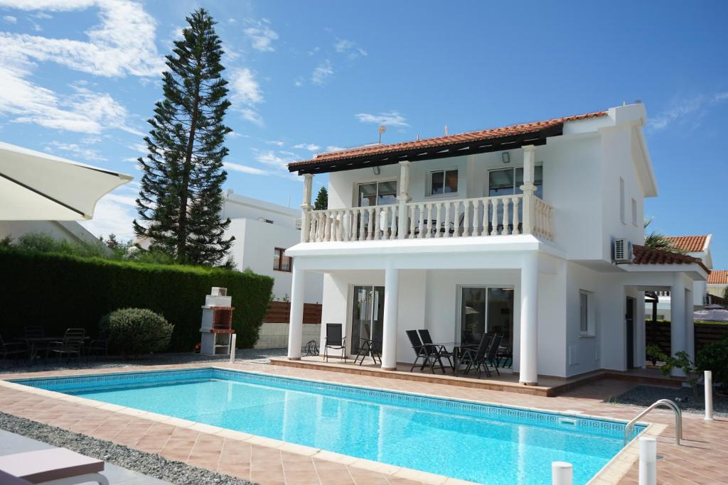 a villa with a swimming pool in front of a house at Villa Coral Cove in Peyia